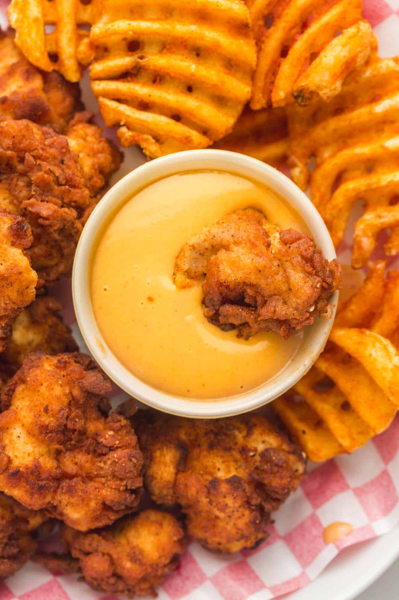 a small bowl of chick fil a sauce surrounded by chicken nuggets and waffle fries