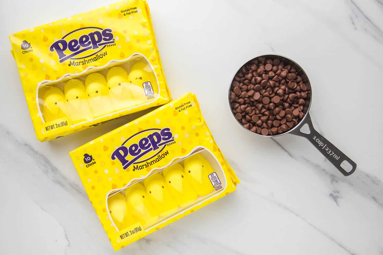 Two packages of peeps and a half cup full of chocolate chips on a counter