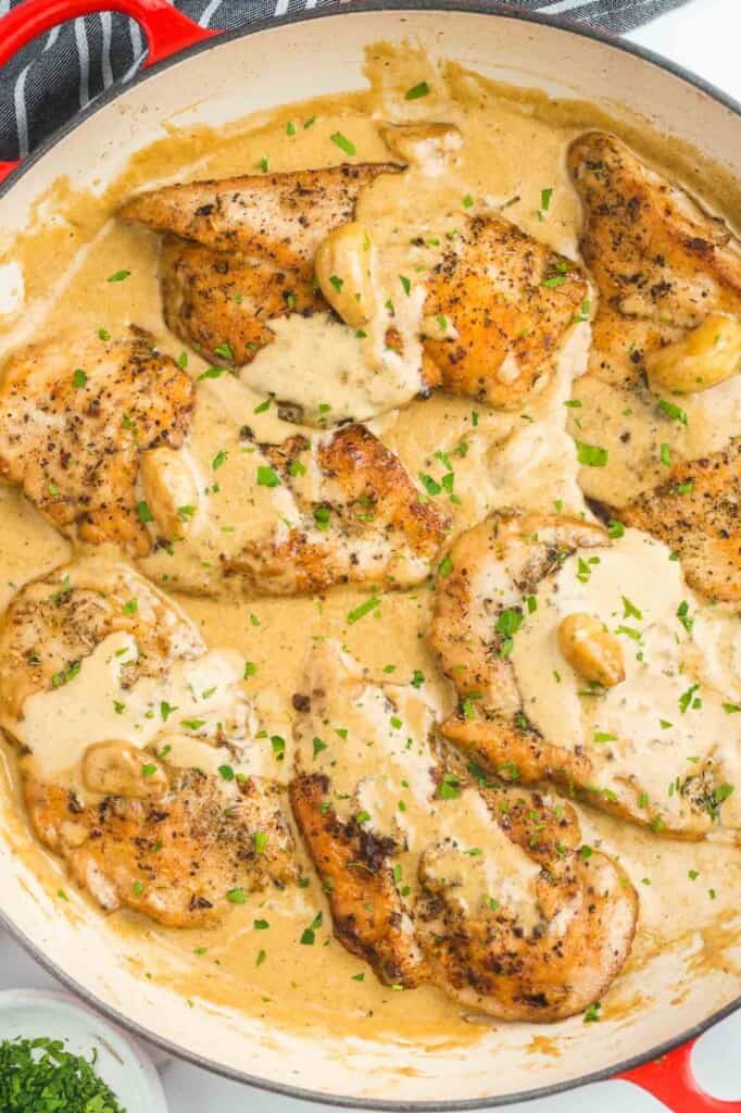 browned boneless skinless chicken breasts in a creamy sauce, inside of a skillet