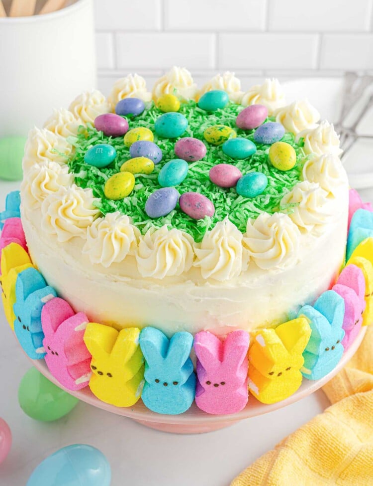 Easter layer cake decorated with peeps, green coconut grass, and M&M's easter eggs.