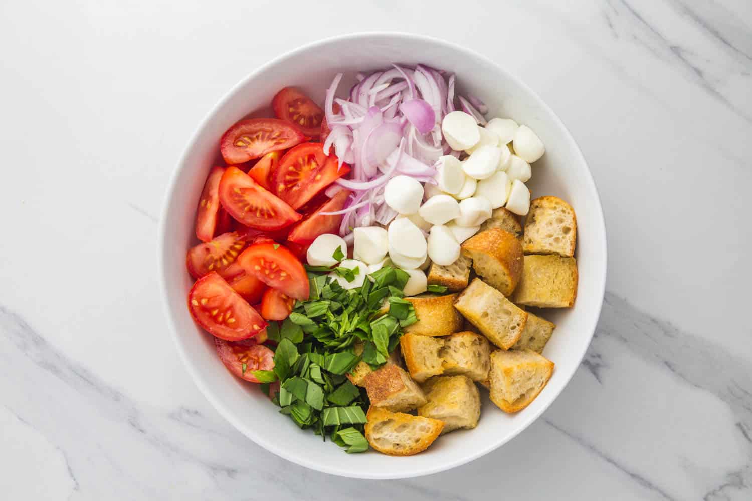 panzanella ingredients in a large bowl before being dressed and tossed.