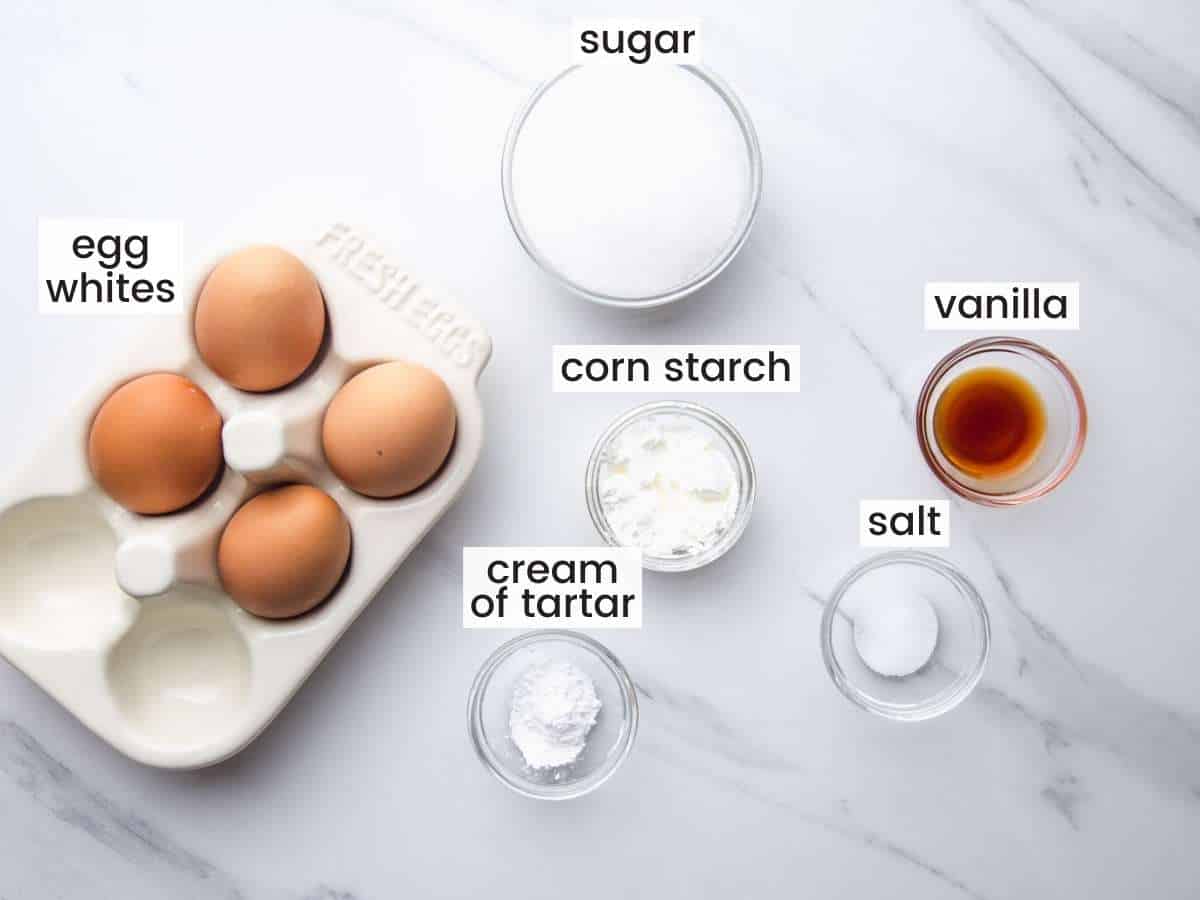 The ingredients for making french meringue for lemon pie, measured into separate bowls on a marble countertop