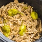 shredded mississippi chicken and pepperoncini in a black slow cooker.