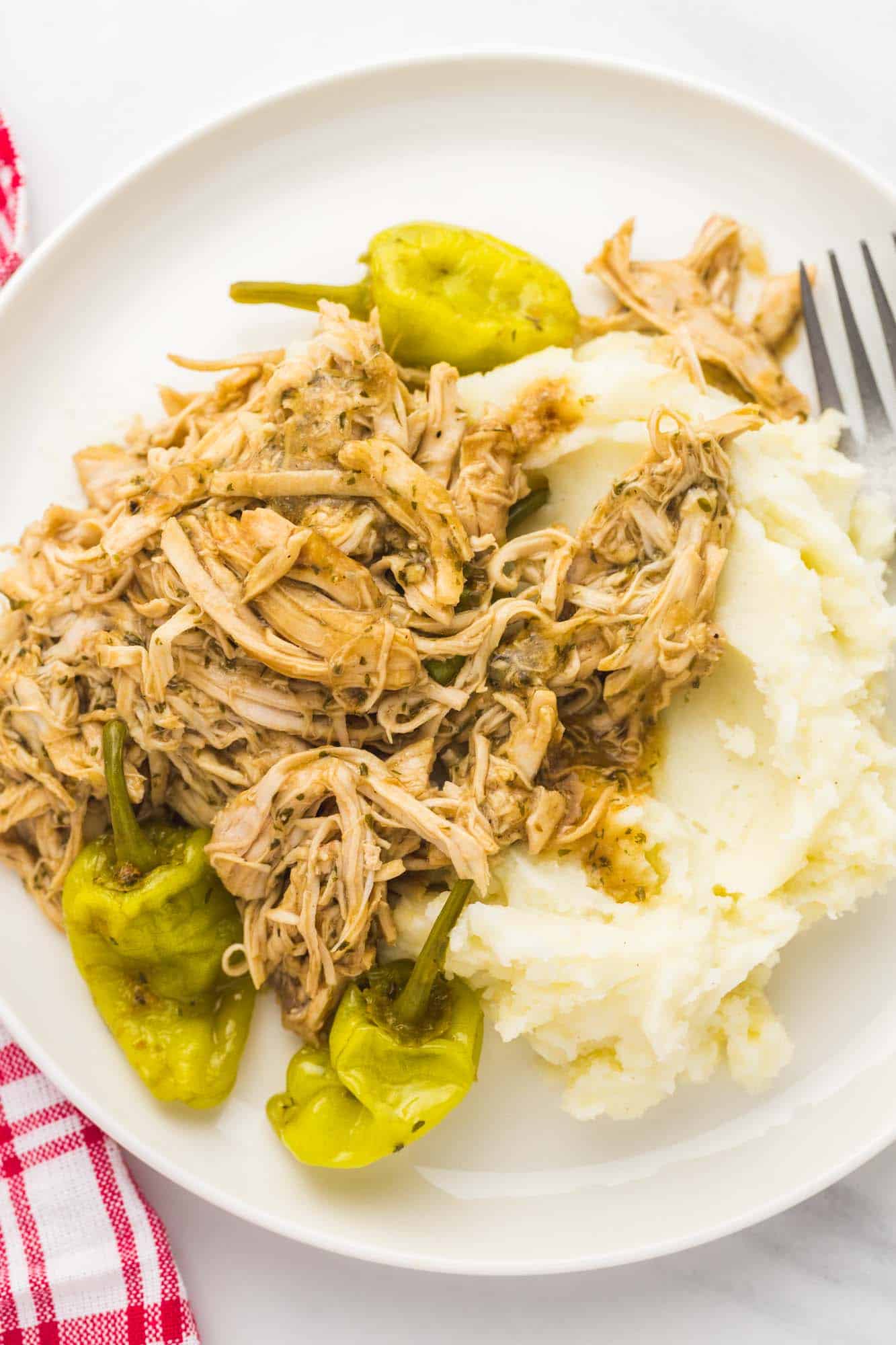 a white plate of mississippi chicken and mashed potatoes