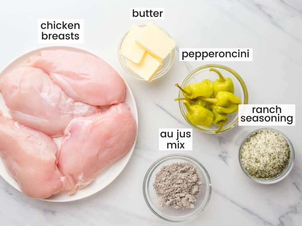 the ingredients for crock pot mississippi chicken in small bowls on a marble counter, viewed from above