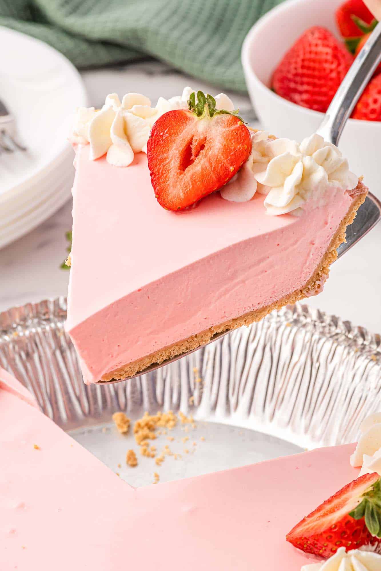 a large slice of no bake strawberry pie is being lifted from the pan with a cake server. 