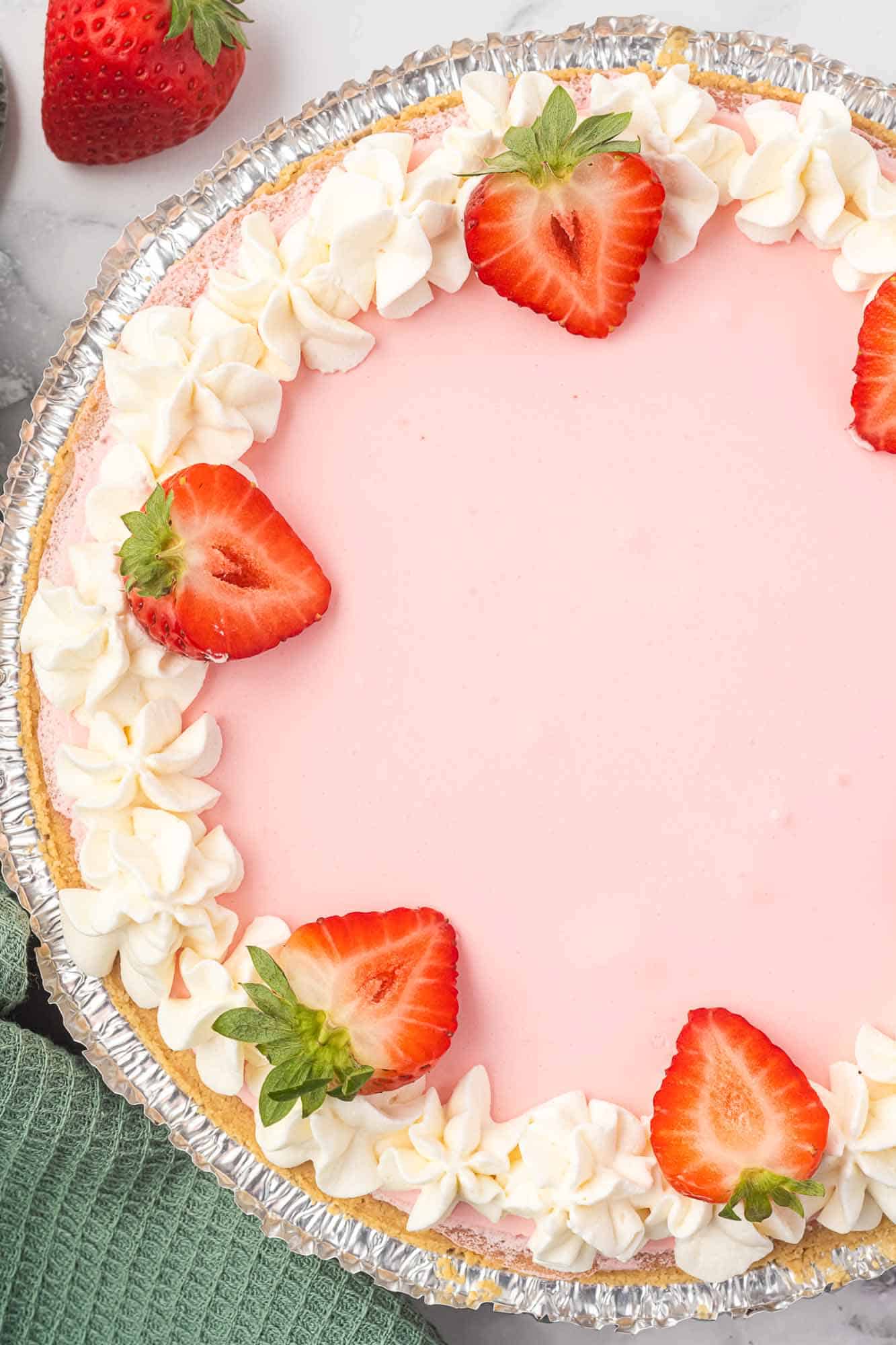a whole no bake strawberry pie viewed from above. Whipped cream and strawberries garnish the edge of the pie.