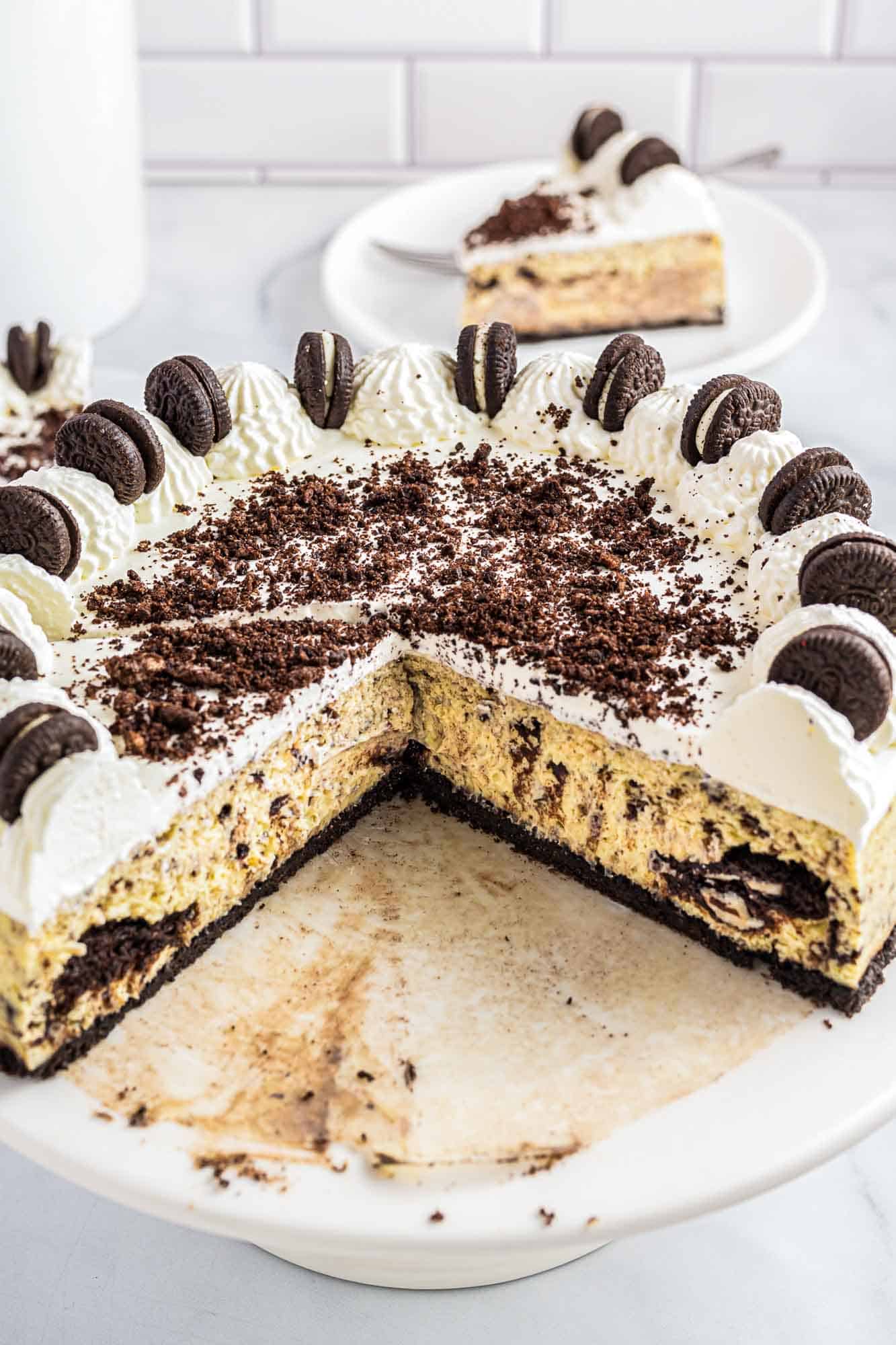 Sliced baked oreo cheesecake to show the texture inside of the cake, on a white cake stand.