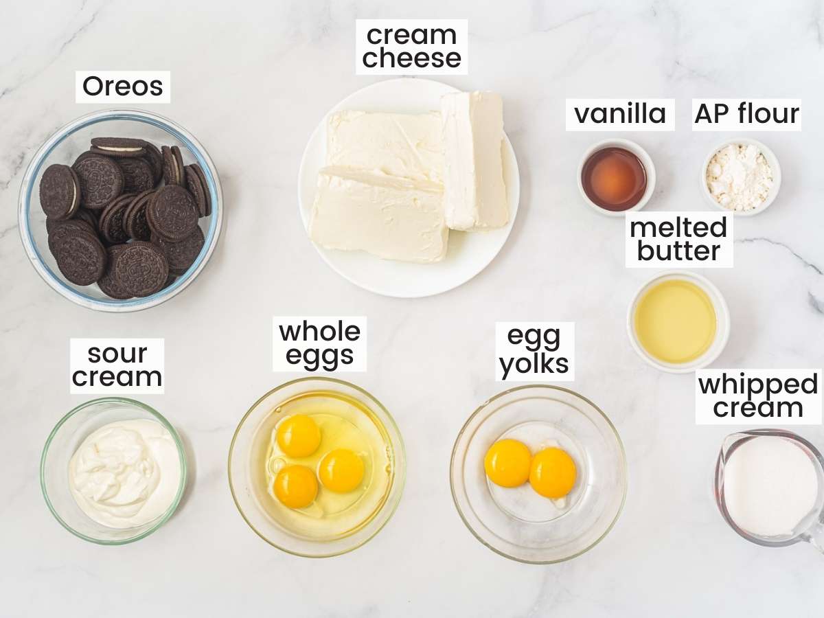 Ingredients needed to make Oreo cheesecake including Oreos, cream cheese, eggs, sour cream, vanilla, butter, flour.