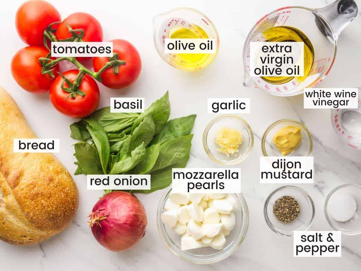 the ingredients in panzanella salad measured into bowls and laid out on a countertop