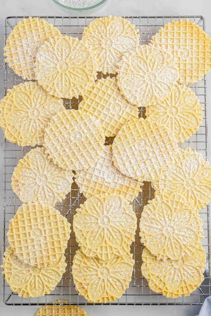 Pizzelles with powdered sugar on a wire rack