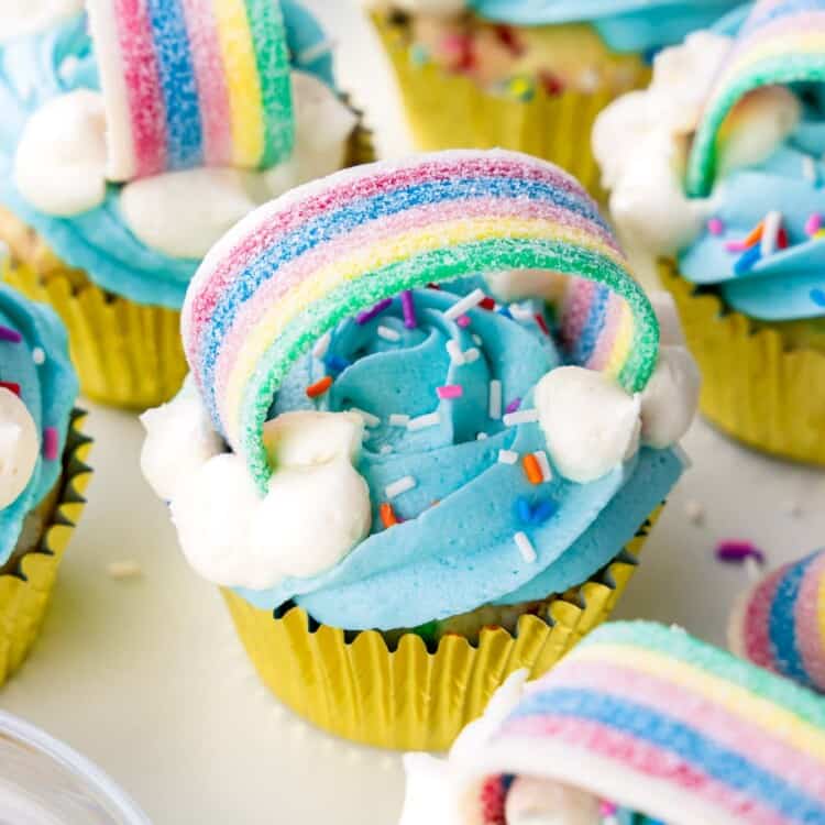 Rainbow cupcakes decorated with blue buttercream and rainbow stip candy and sprinkles