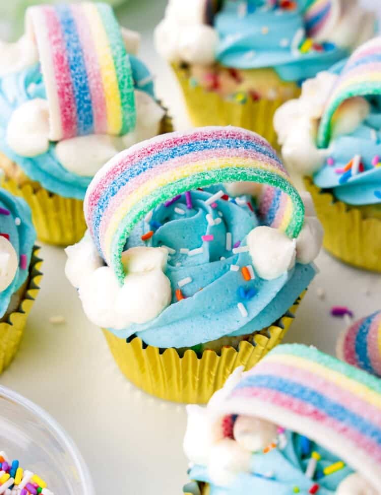 Rainbow cupcakes decorated with blue buttercream and rainbow stip candy and sprinkles