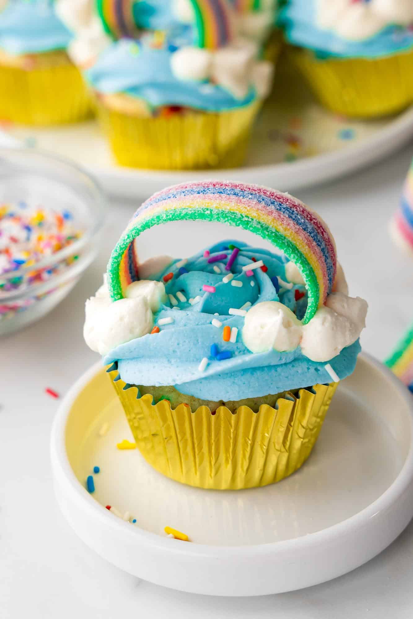 Rainbow cupcakes in a gold wrapper, placed on a small white plate
