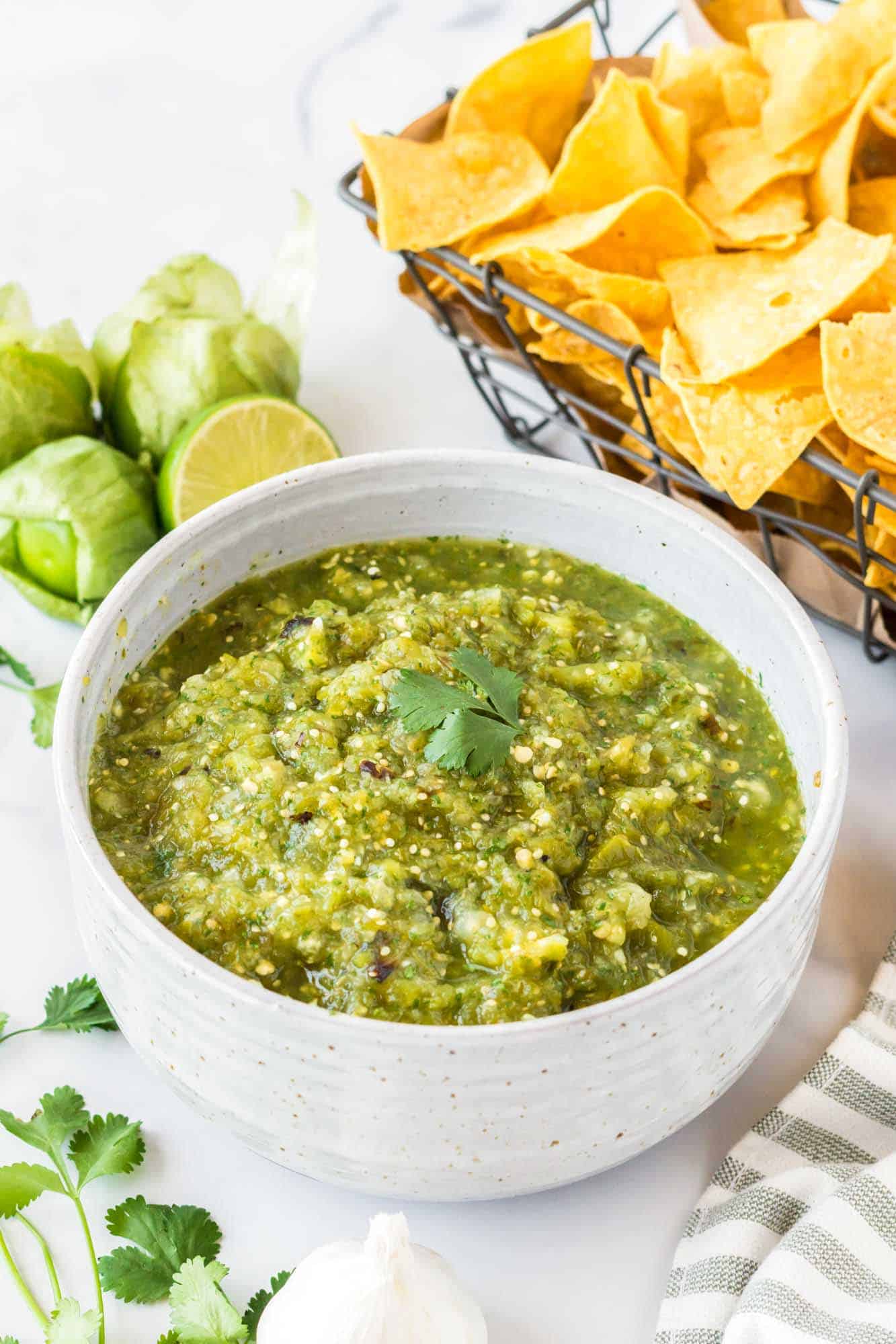 Salsa verde in a white bowl with chips on the side