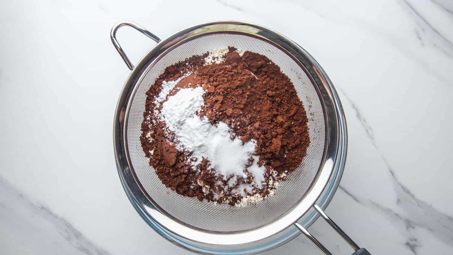 the dry ingredients for chocolate cake in a sieve