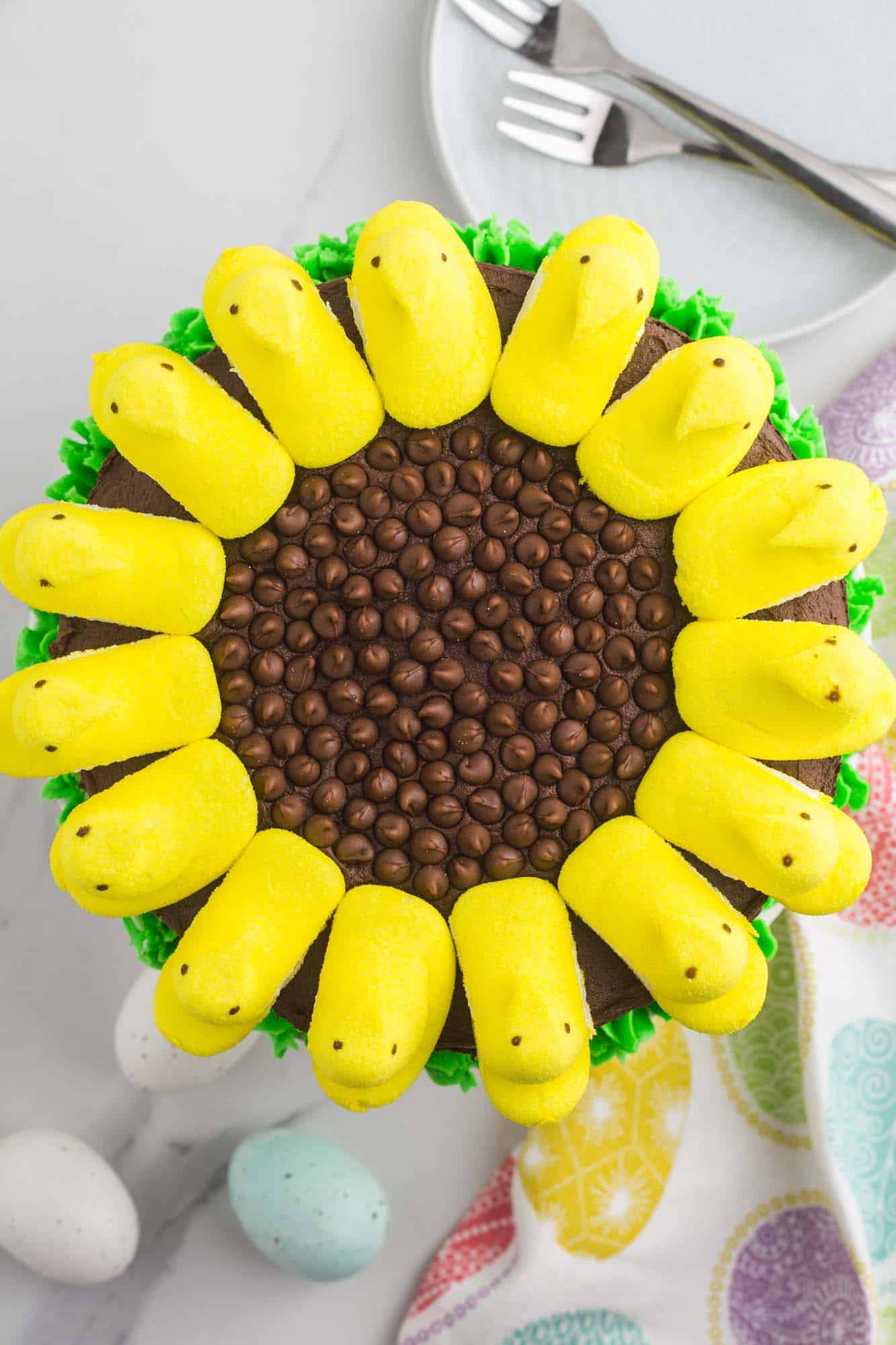a chocolate cake viewed from above, decorated to look like a sunflower with yellow marshmallow peeps and chocolate chips
