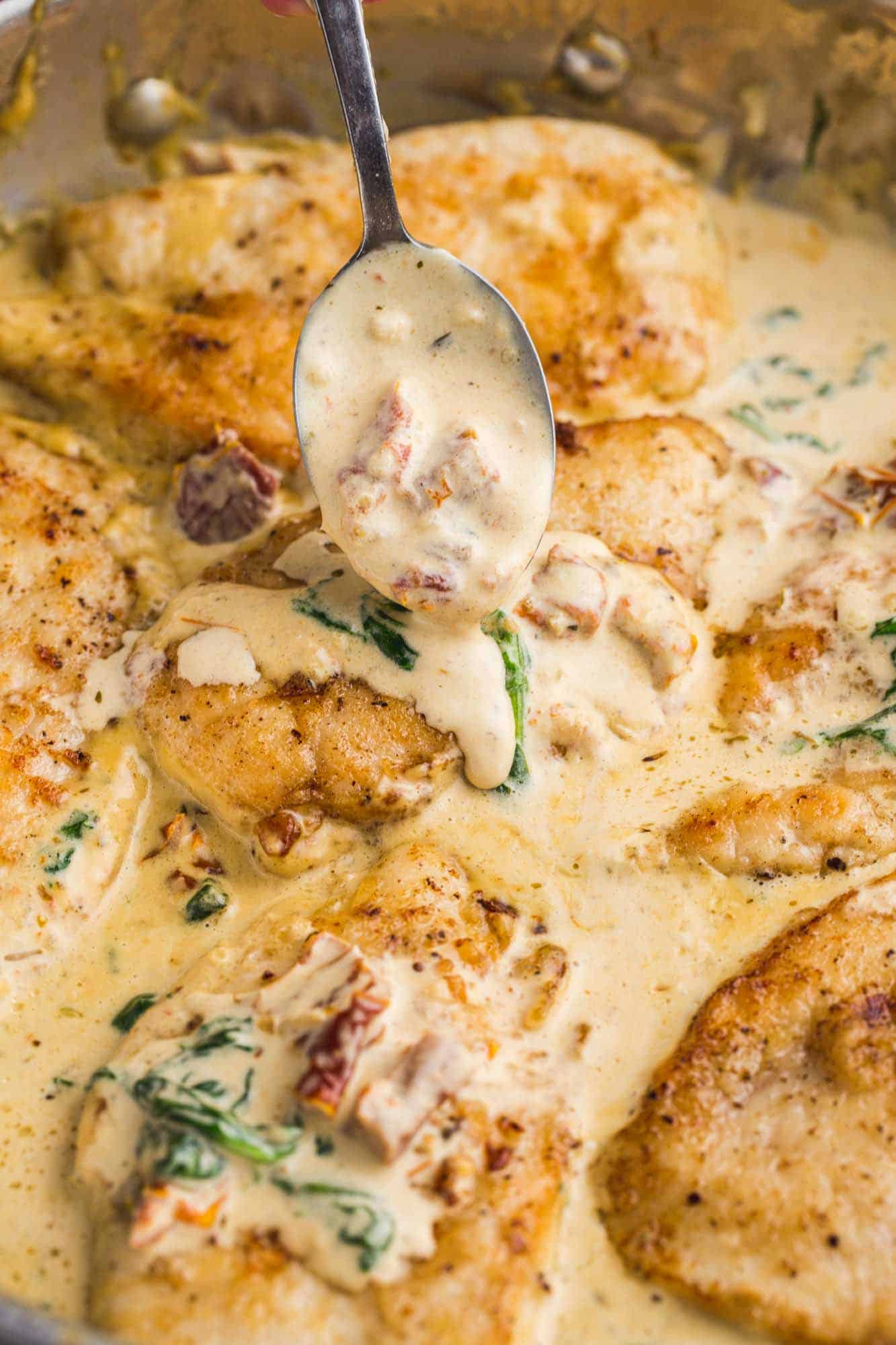 Drizzling cream sauce over chicken with a spoon