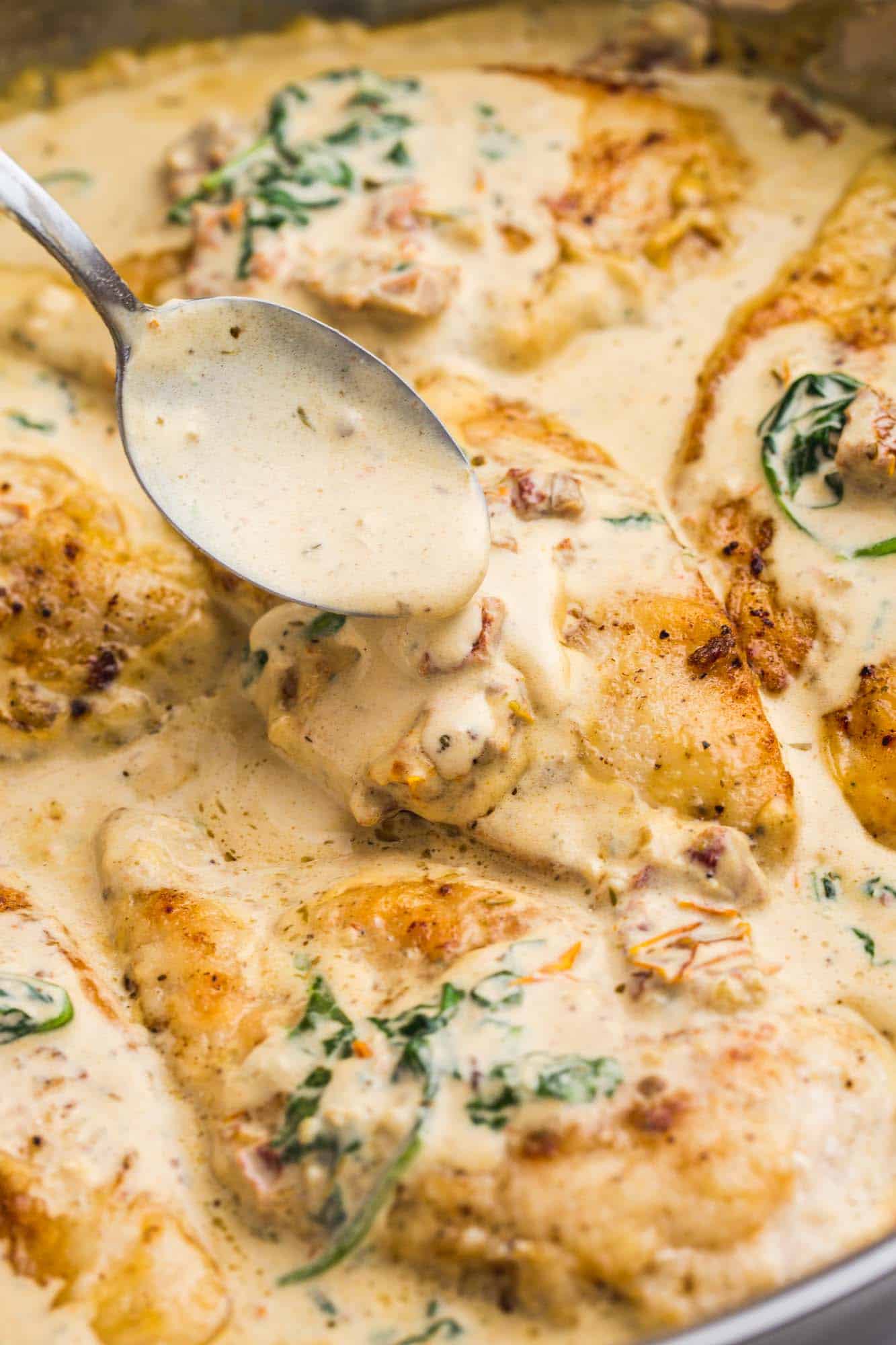 Drizzling cream sauce over chicken in the pan