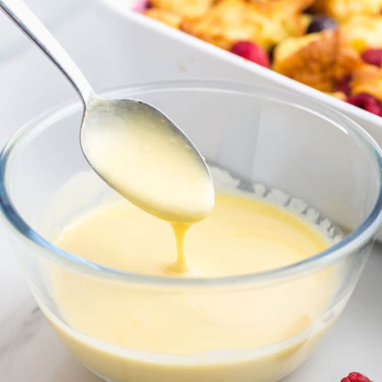 Simple vanilla sauce in a small glass bowl, and a spoon.