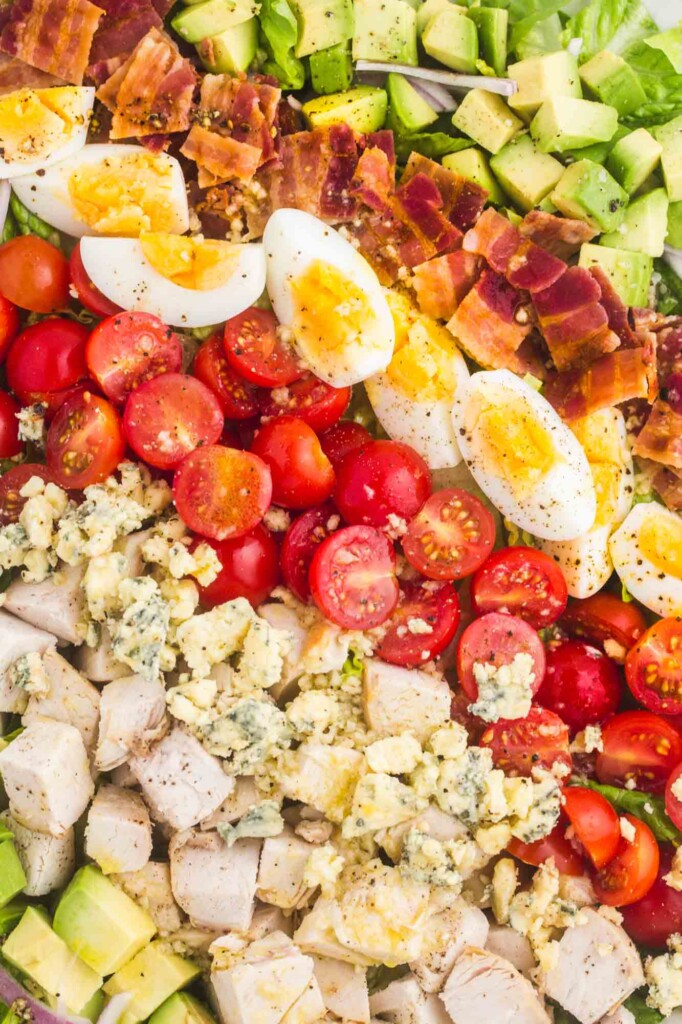 closeup view of a chicken cobb salad made with layers of avocado, chicken, tomato, egg, bacon, and lettuce