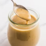 a small jar of creamy balsamic dressing being served with a teaspoon.
