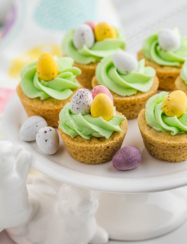 Easter cookie cups placed on a bunny cake stand, decorated with chocolate mini eggs