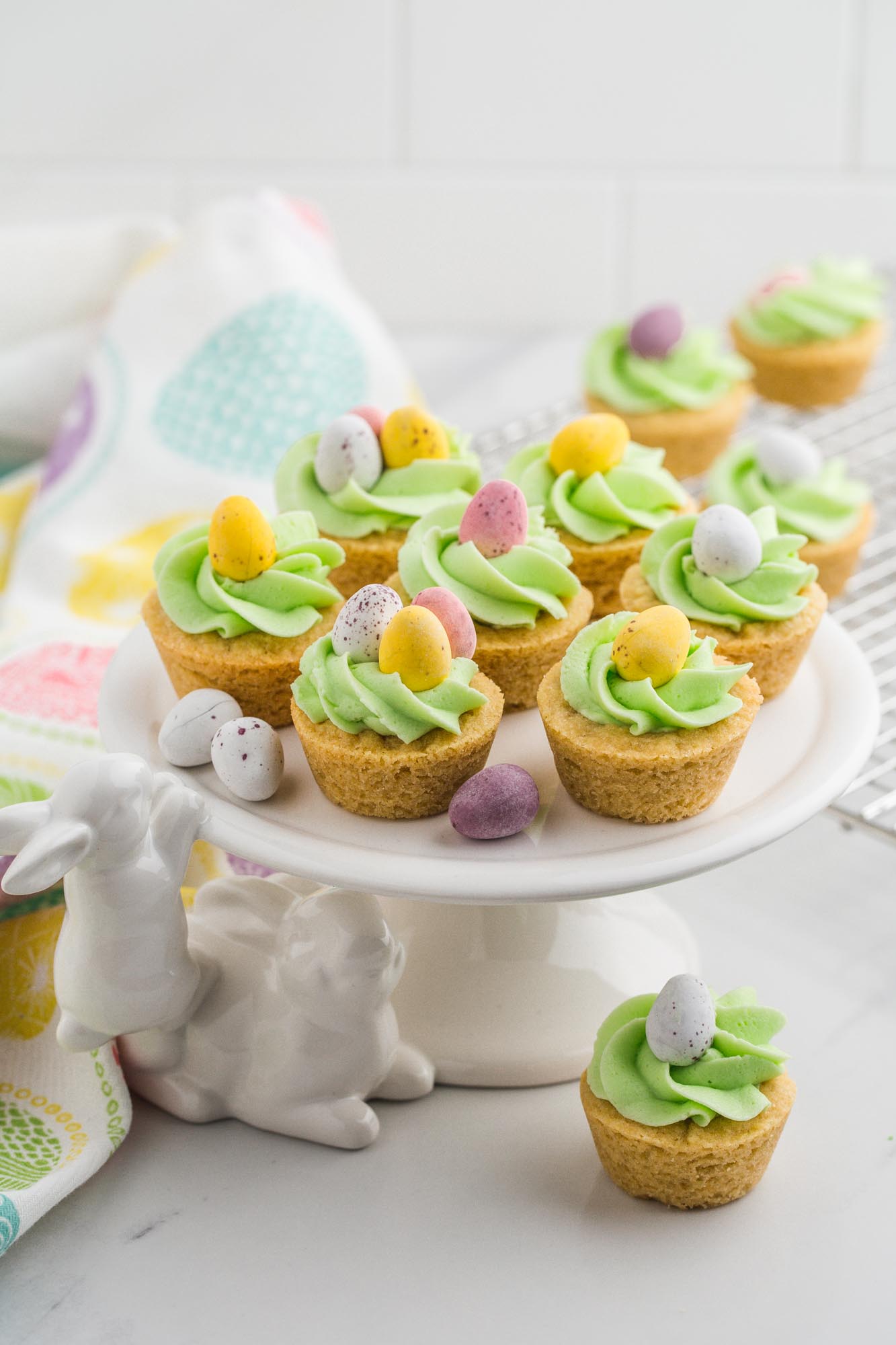 Easter basket cookie cups presented on a white bunny cake stand