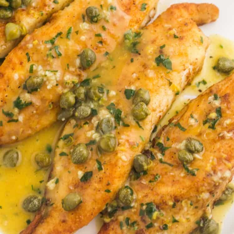 Tilapia fillets topped with piccata sauce and capers on a rectangular platter
