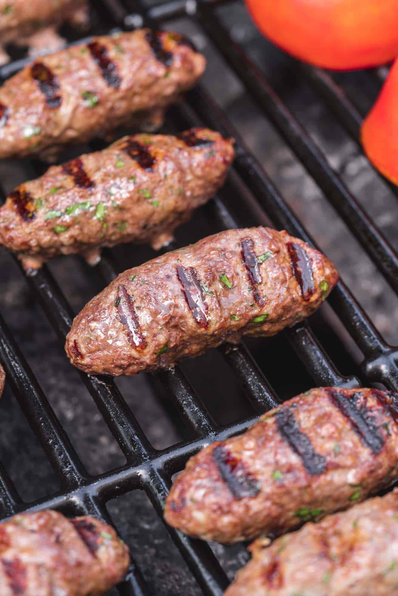 Grilled Kaftas on the grill with tomatoes on the side of the grill