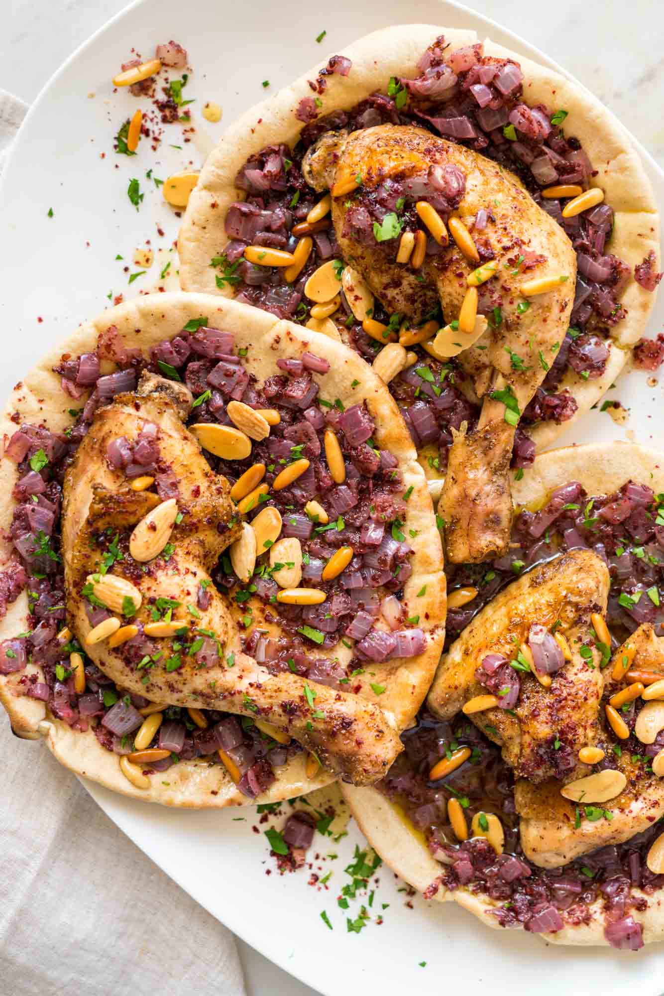 Overhead shot of musakhan chicken parts served on flatbreads with sumac onions