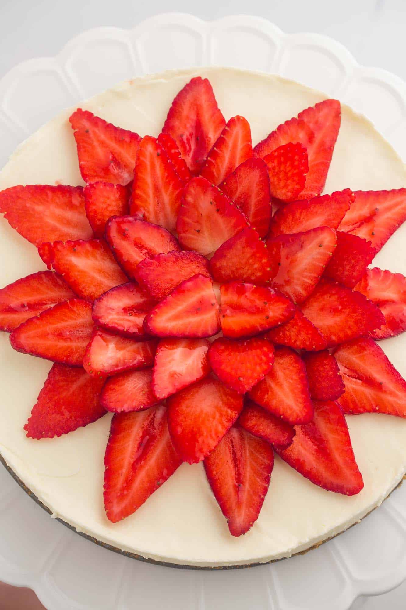 Cheesecake topped with sliced strawberries in a flower pattern, viewed from above