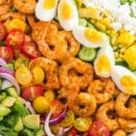 a large shrimp cobb salad with rows of shrimp, eggs, veggies, and cheese on top
