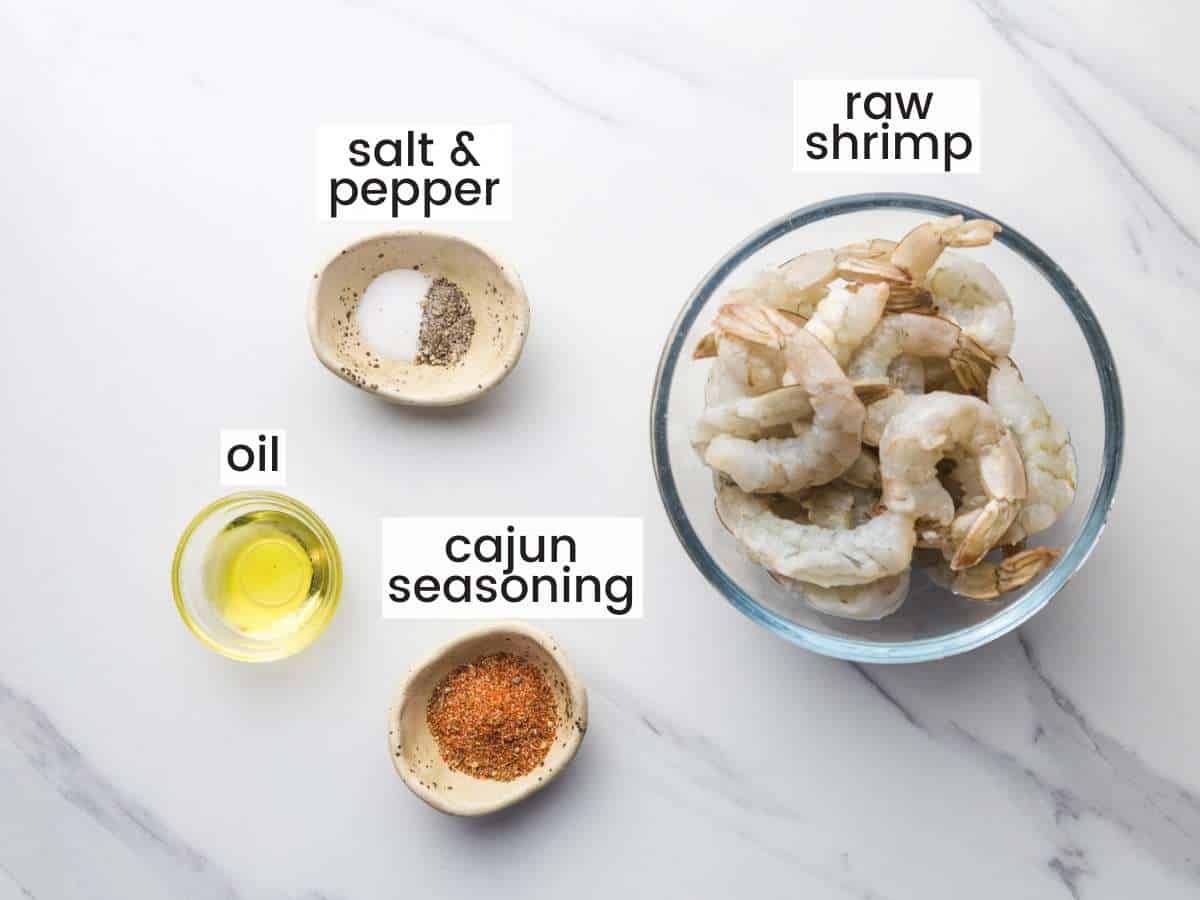 shrimp, seasonings, and oil in separate bowls on a marble counter