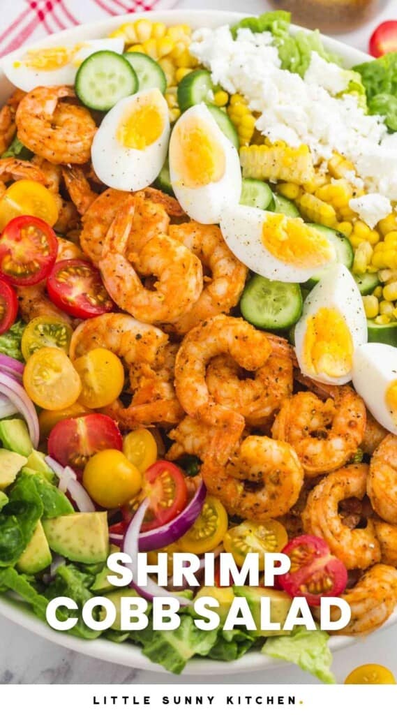 a large shrimp cobb salad with rows of shrimp, eggs, veggies, and cheese on top. Text at bottom of picture says Shrimp Cobb Salad