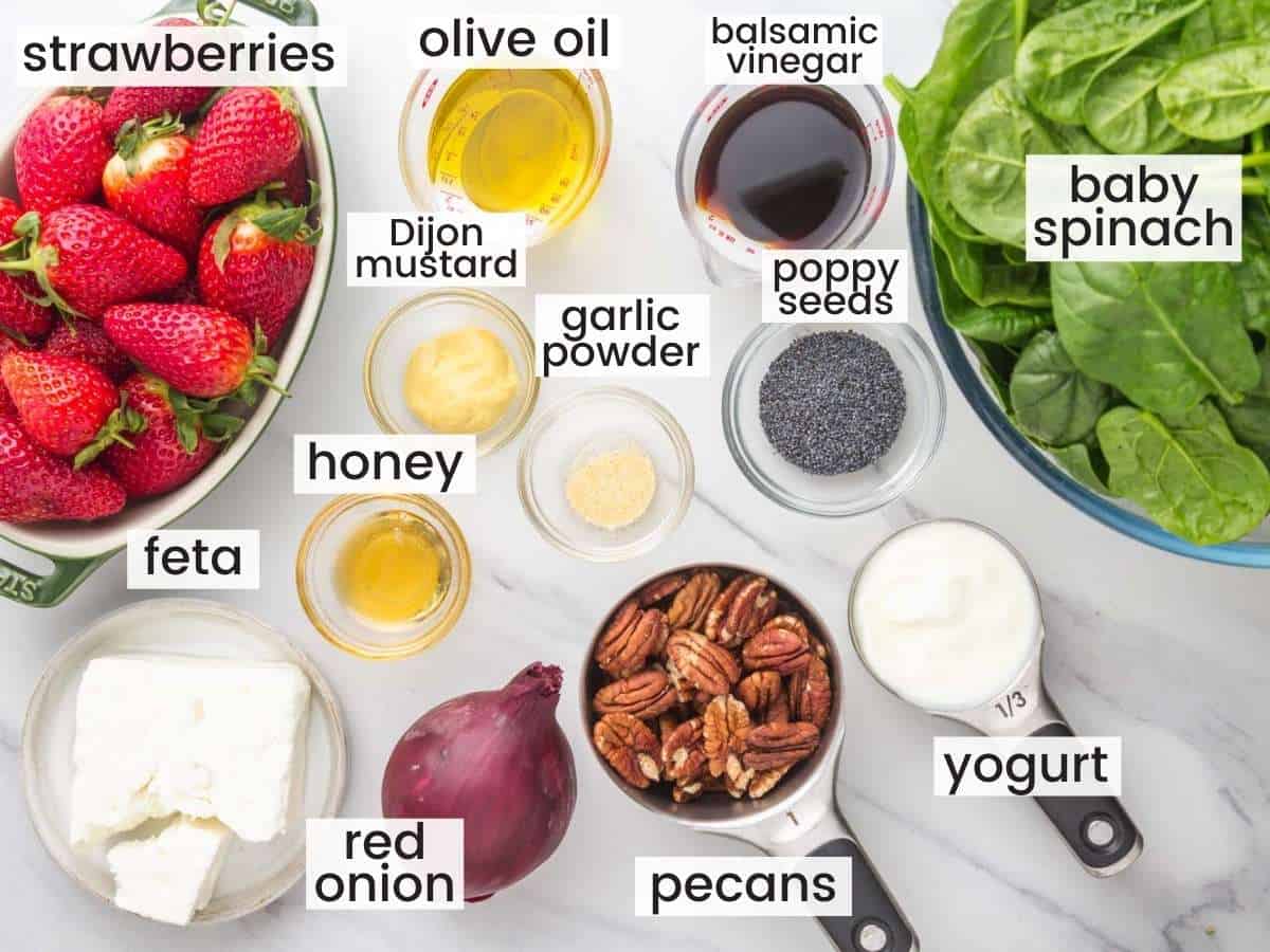 The ingredients for strawberry spinach salad on a marble counter