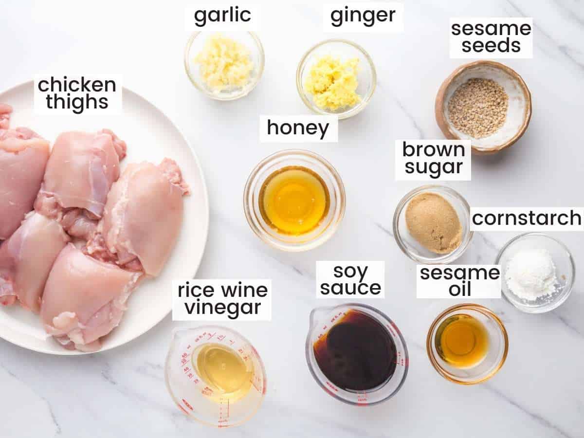 The ingredients for teriyaki chicken measured into separate bowls on a marble countertop, viewed from above