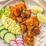 a neatly assembled teriyaki salmon rice bowl with avocado, cucumber, radish, and lime