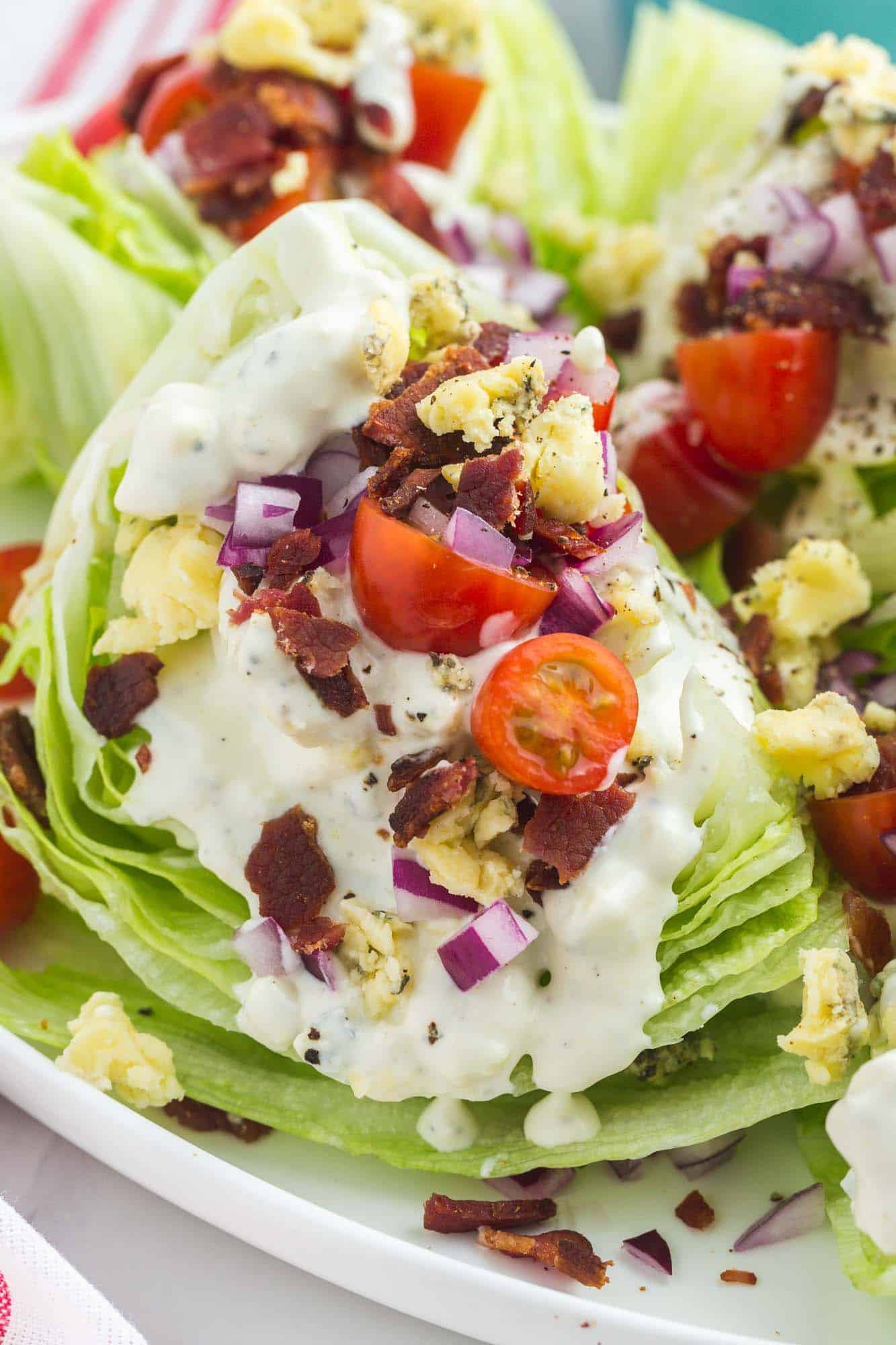wedge salad topped with blue cheese dressing, red onion, bacon, and cherry tomatoes. 