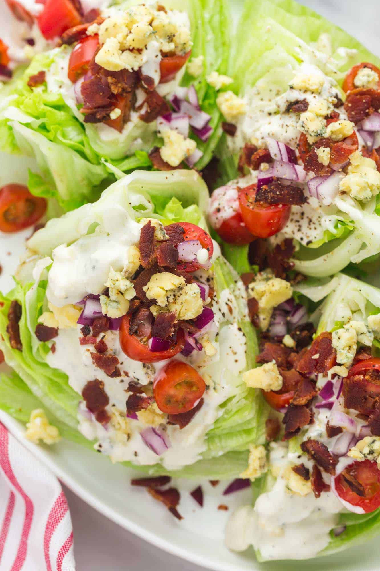 a platter filled with wedges of iceberg lettuce topped with bacon, blue cheese, tomato, and onion