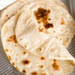 Yogurt flatbreads placed on an aluminum tray, with the front flatbread folded to show that it's pliable.