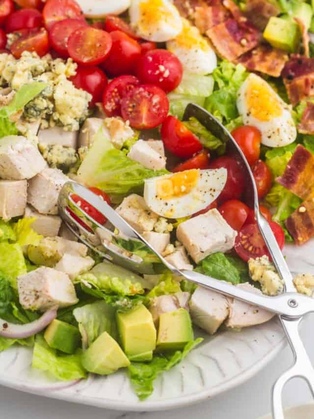 Stainless steel salad tongs serving a cobb salad
