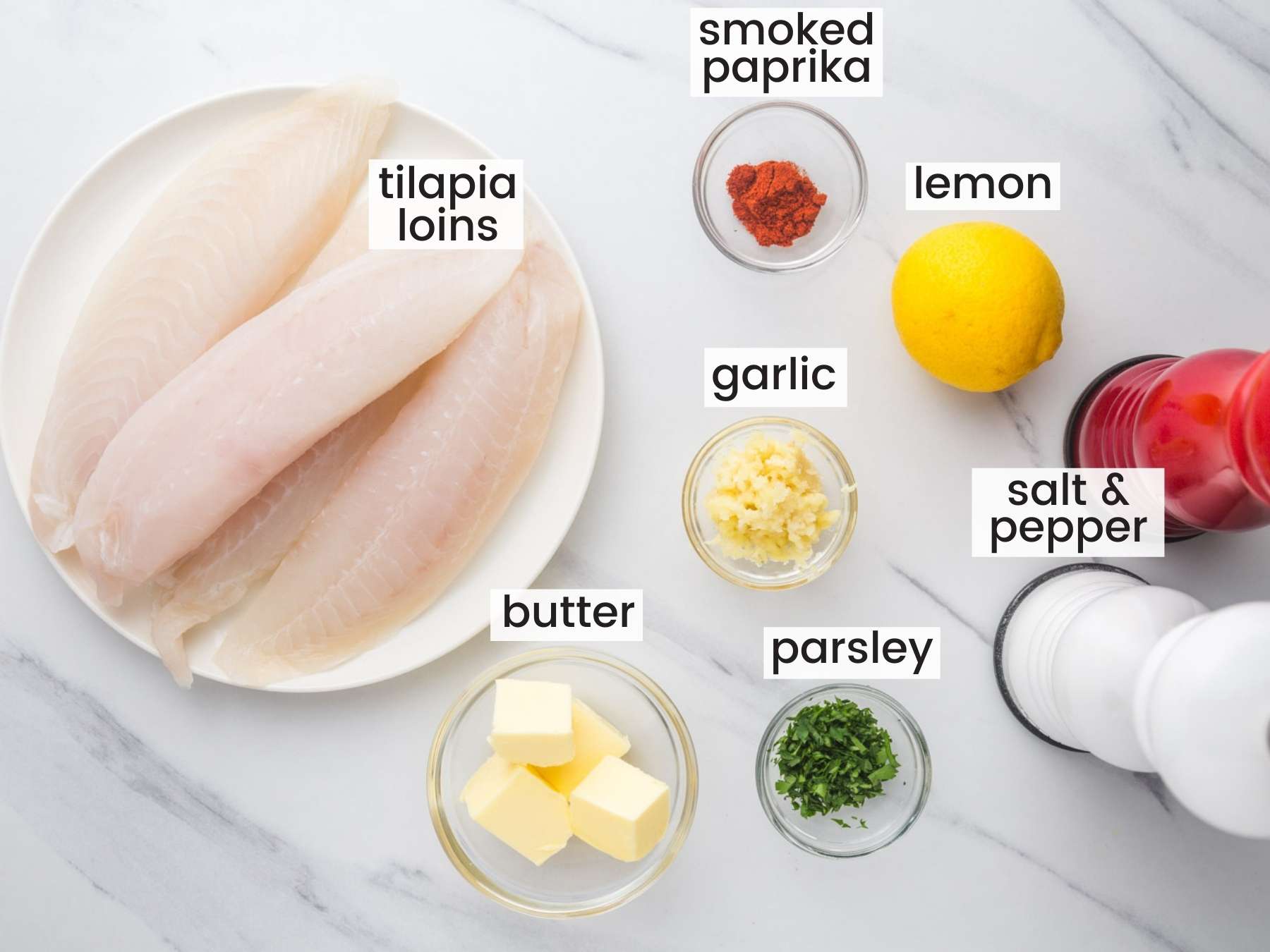 The ingredients for making baked tilapia, on a marble countertop, viewed from above