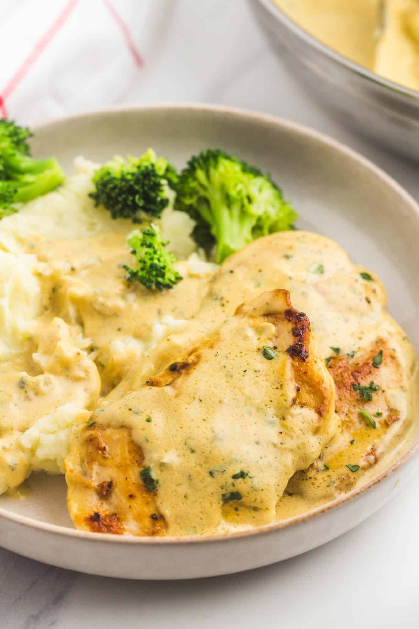 Chicken cutlets with creamy garlic sauce on a plate with mashed potatoes and broccoli