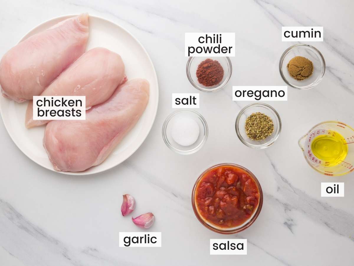 The ingredients for making mexican chicken for nachos, in separate bowls on a marble counter, viewed from above