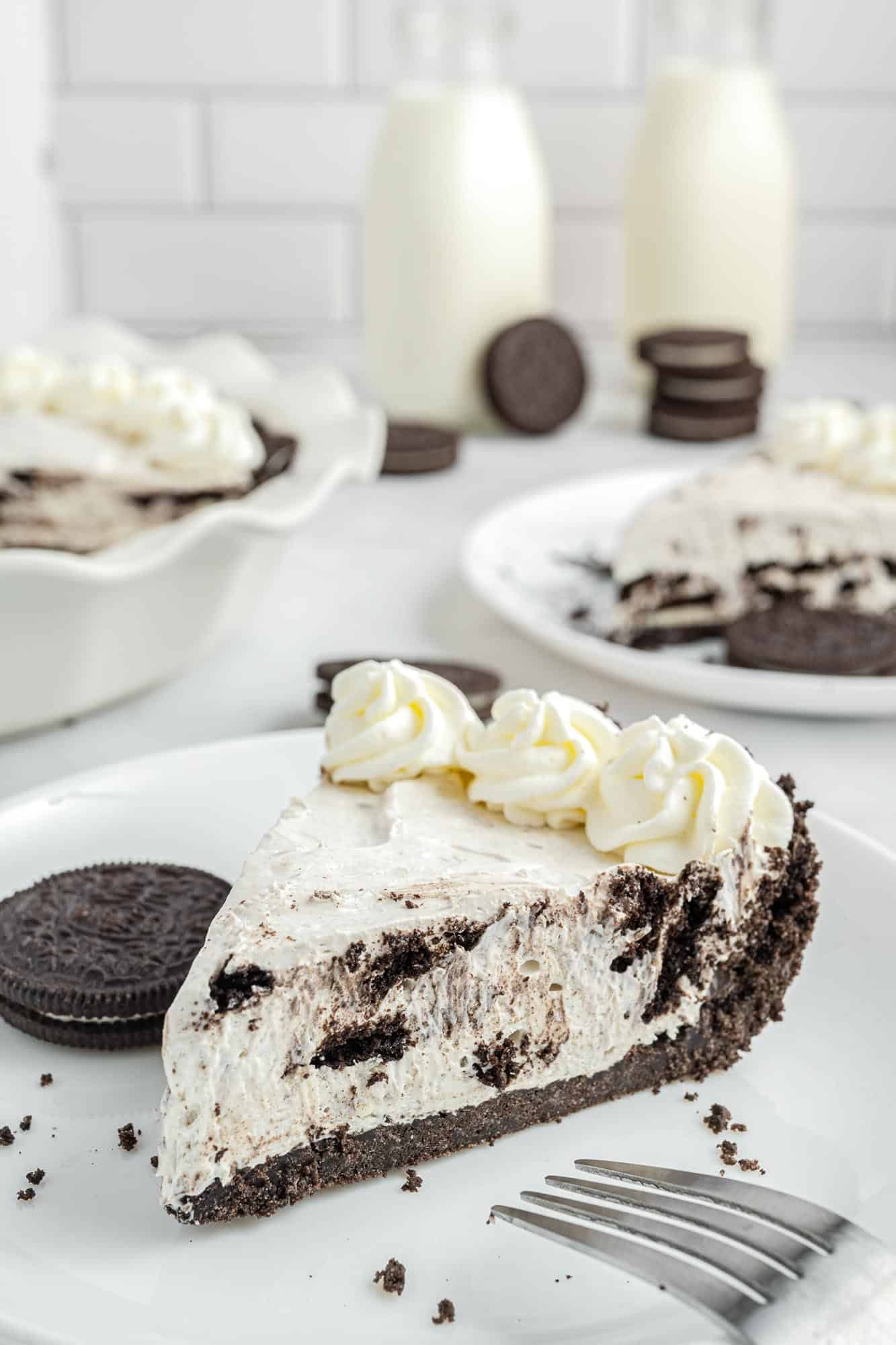a slice of no bake oreo pie on a white plate with an oreo cookie on the side.
