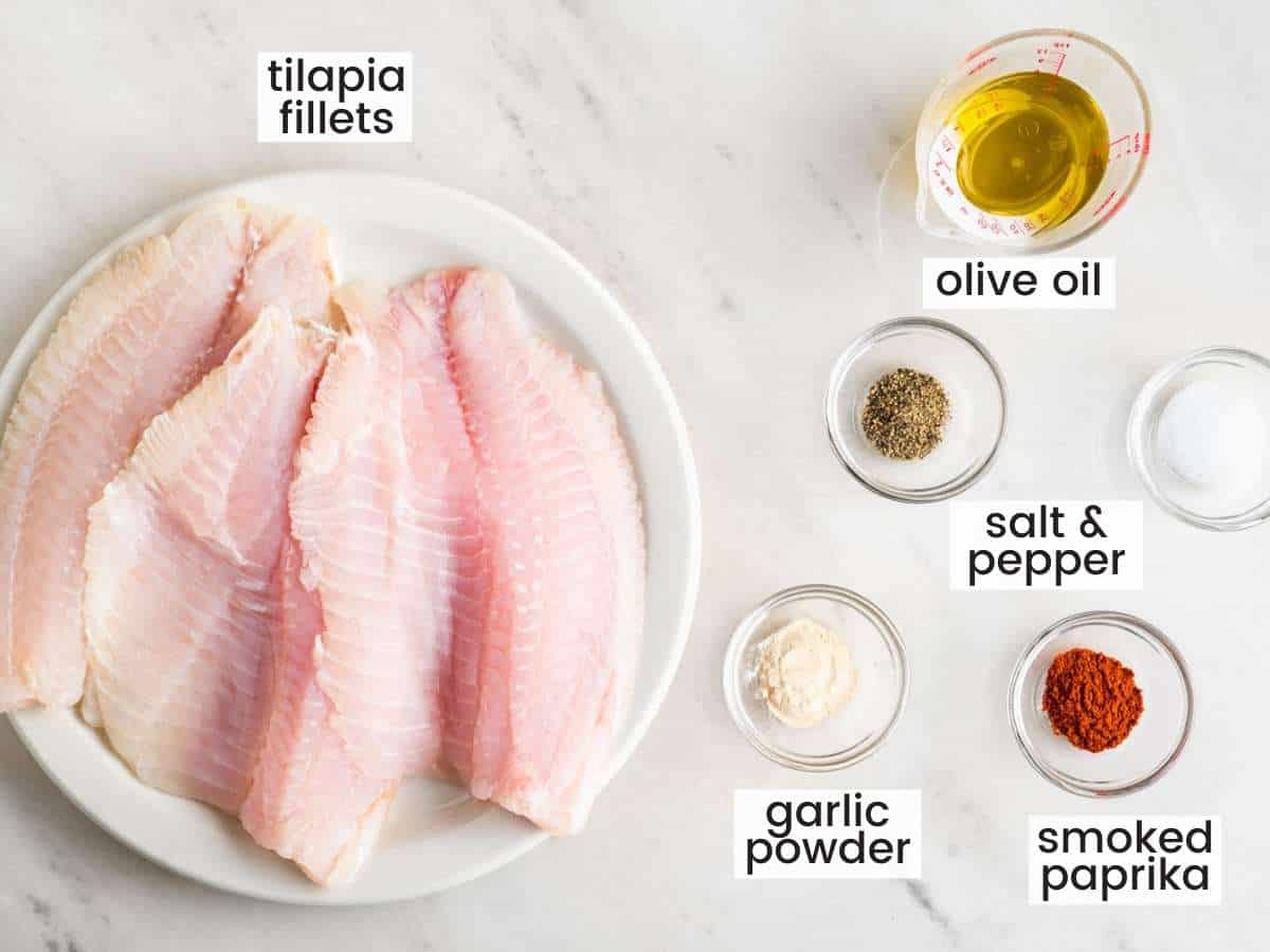 The simple ingredients needed to make pan fried tilapia fillets, in small bowls on the counter, viewed from above