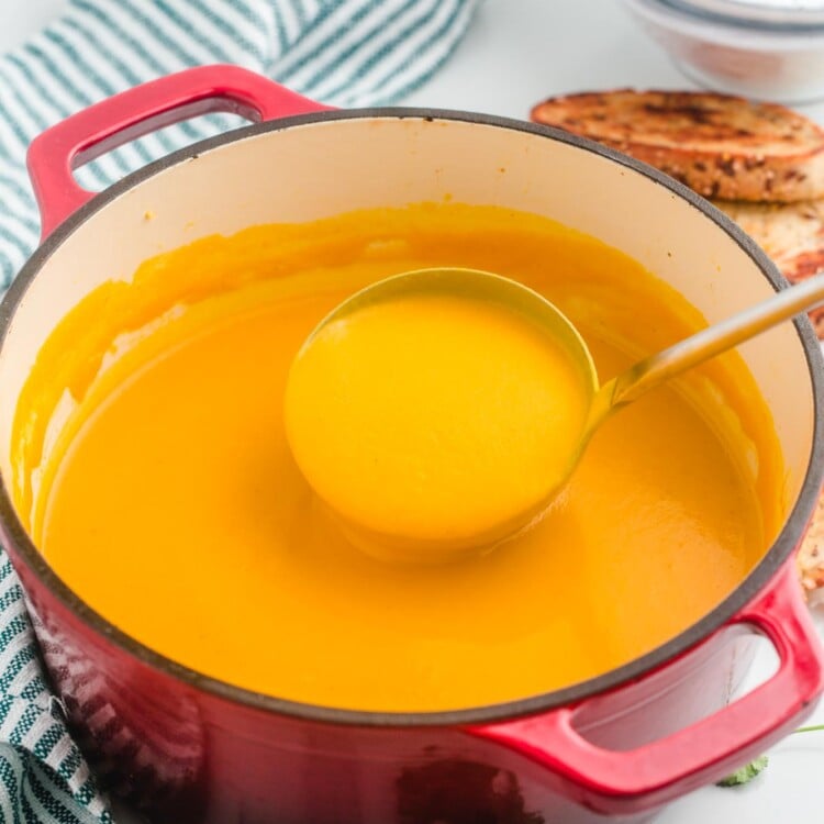 Sweet Potato soup in a large red dutch oven and a soup ladle
