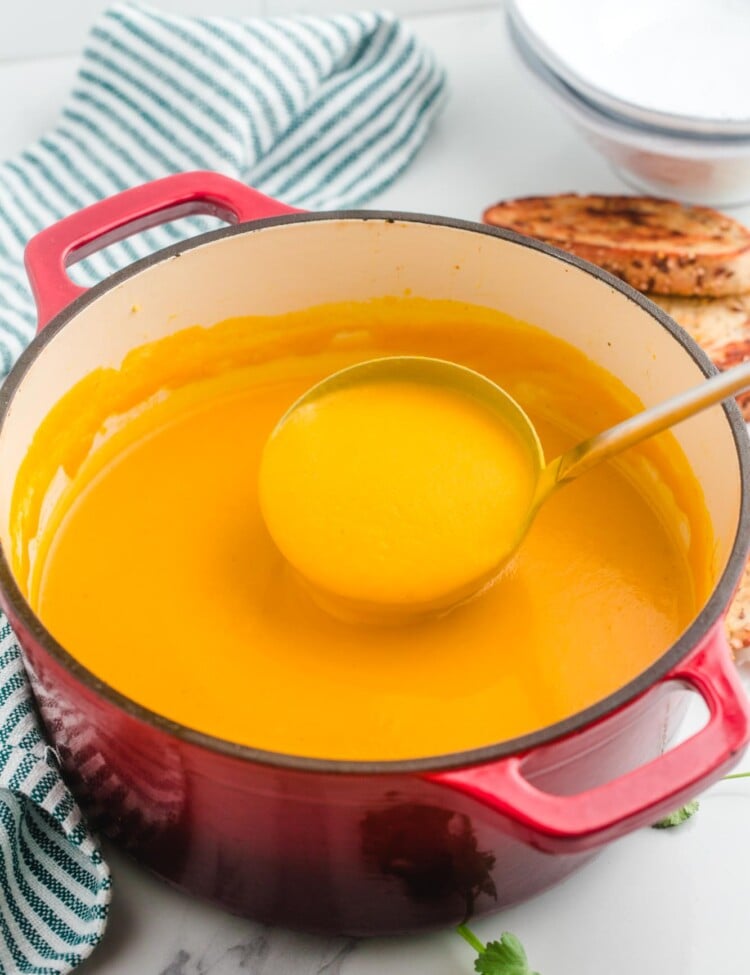 Sweet Potato soup in a large red dutch oven and a soup ladle