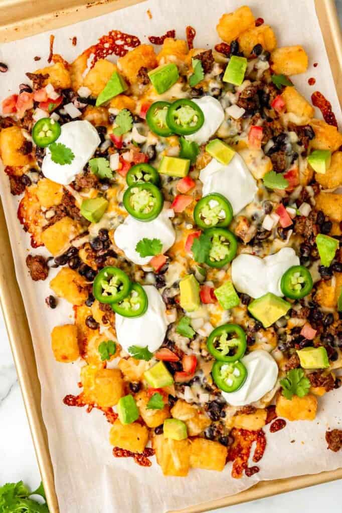 Tater tot nachos topped with jalapeno slices, avocado, sour cream and diced tomato.